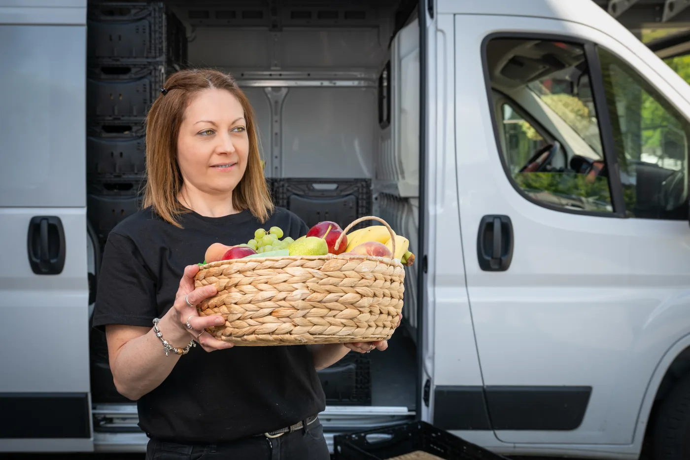 Collaboratrice Firmenfrüchte tenant un panier de fruits préparé devant le véhicule de livraison